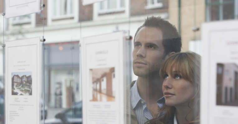 couple looking at house advert in window