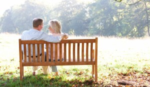 An elderly couple talking on a park bench
