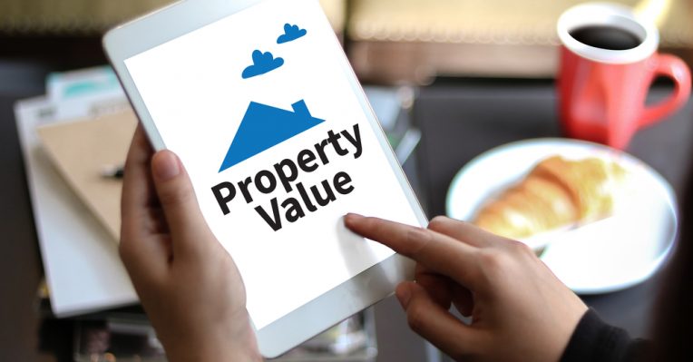 A tablet with the words 'property value' written on it with a breakfast table in the background
