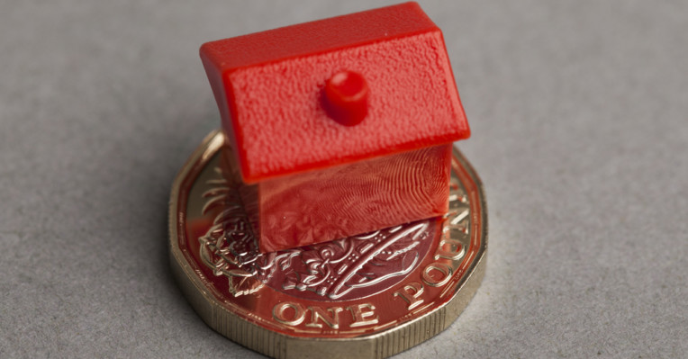an image of a model house on a coin to denote a story about Natwest upping existing customer rates