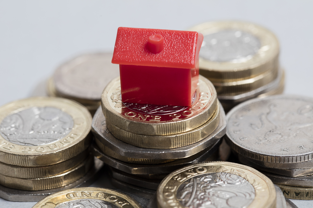 a toy house on top of coin stacks to denote Accord Mortgages' £5k deposit mortgage