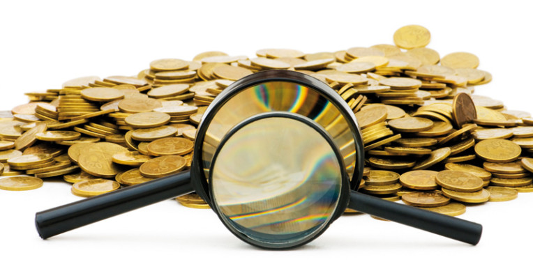 A magnifying glass in front of a pile of money