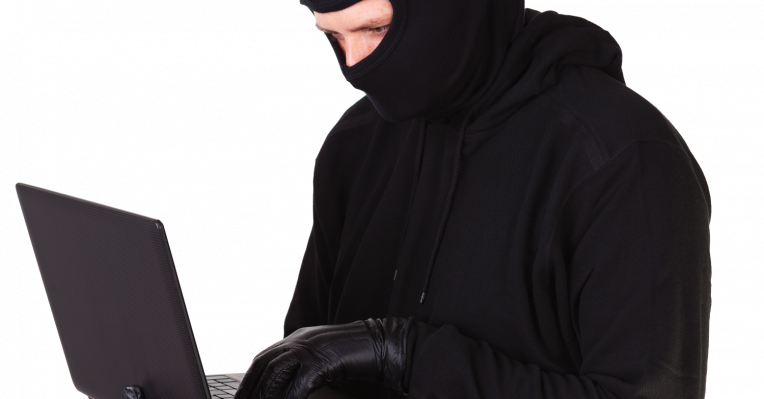Cyber criminal wearing balaclava keying into laptop